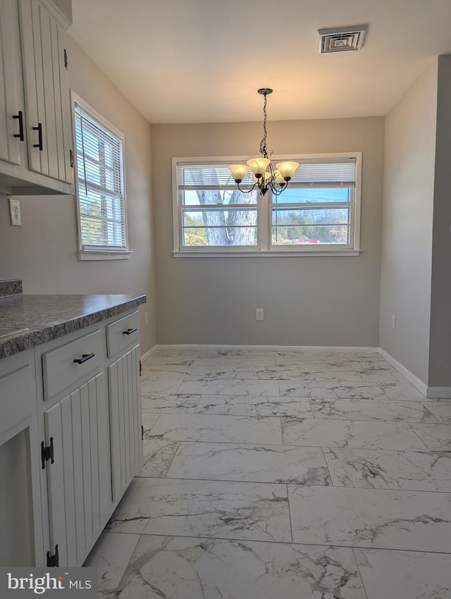 unfurnished dining area with an inviting chandelier