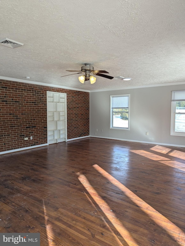 empty room with ornamental molding, brick wall, dark wood-type flooring, and ceiling fan