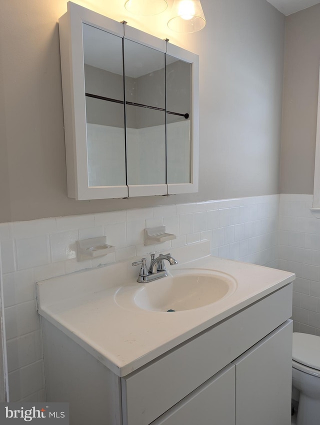 bathroom with vanity, tile walls, and toilet