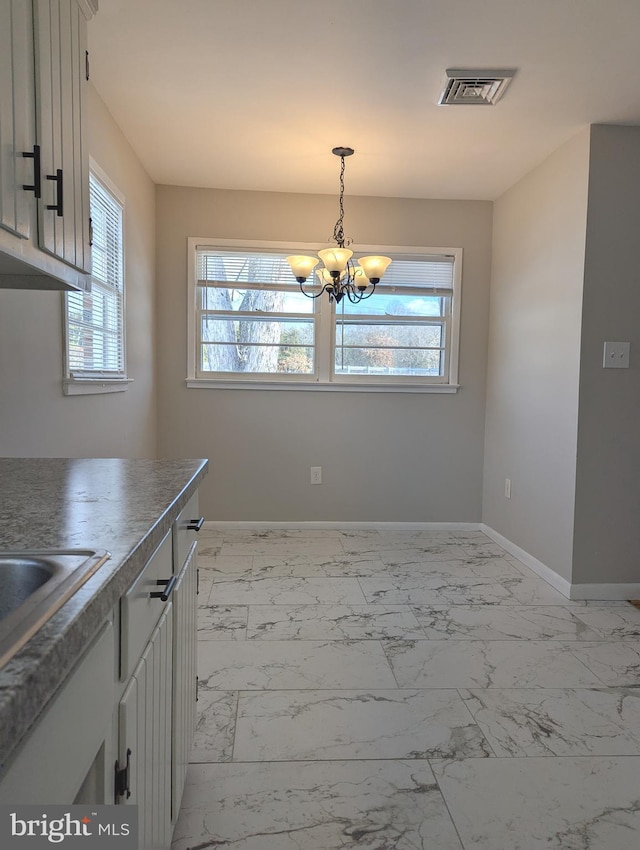 unfurnished dining area featuring sink and a notable chandelier