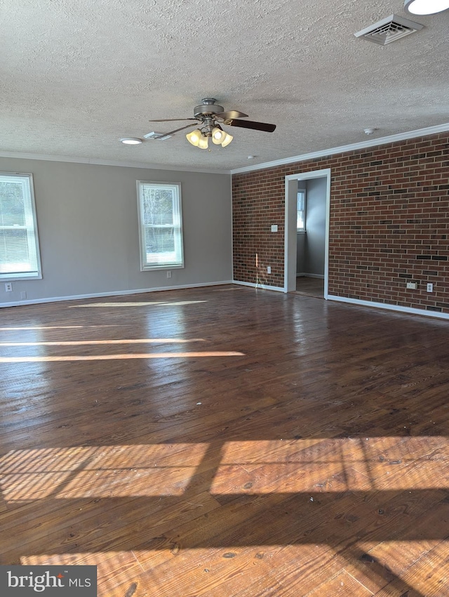 spare room featuring ornamental molding, brick wall, dark wood-type flooring, and a textured ceiling