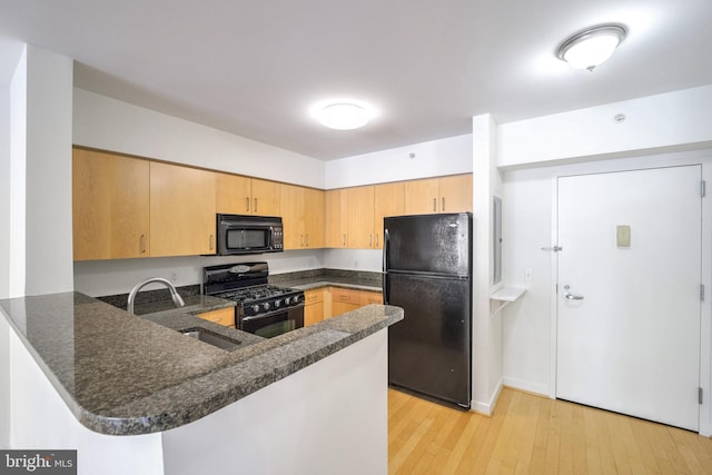 kitchen featuring light wood-type flooring, sink, kitchen peninsula, and black appliances