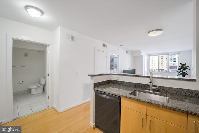 kitchen with black dishwasher, light hardwood / wood-style floors, dark stone counters, and sink