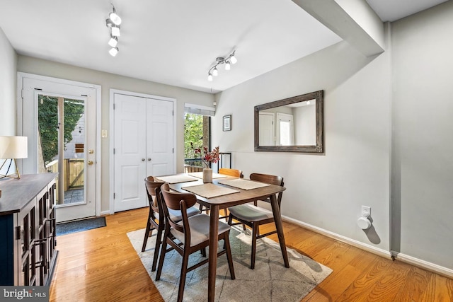 dining area with light hardwood / wood-style floors and track lighting