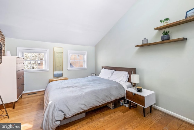 bedroom with light wood-type flooring and vaulted ceiling