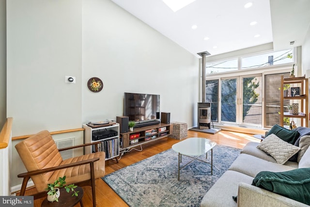 living room featuring hardwood / wood-style floors, a wood stove, and high vaulted ceiling