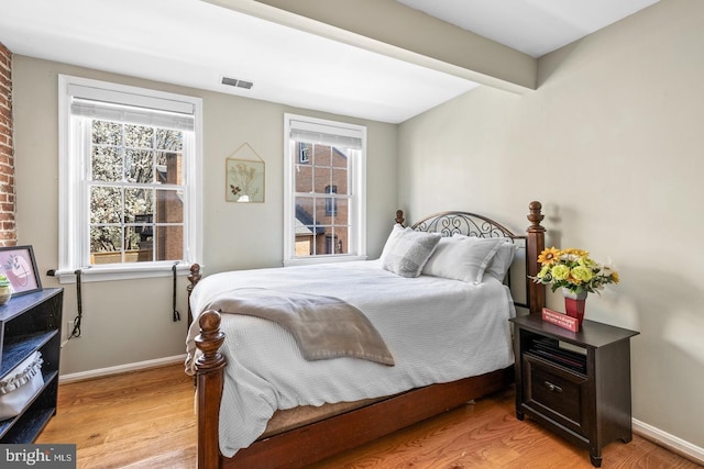 bedroom with beamed ceiling and light wood-type flooring