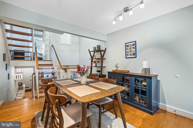 dining space with rail lighting and light hardwood / wood-style flooring