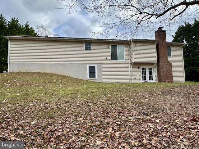 rear view of property featuring a lawn and french doors