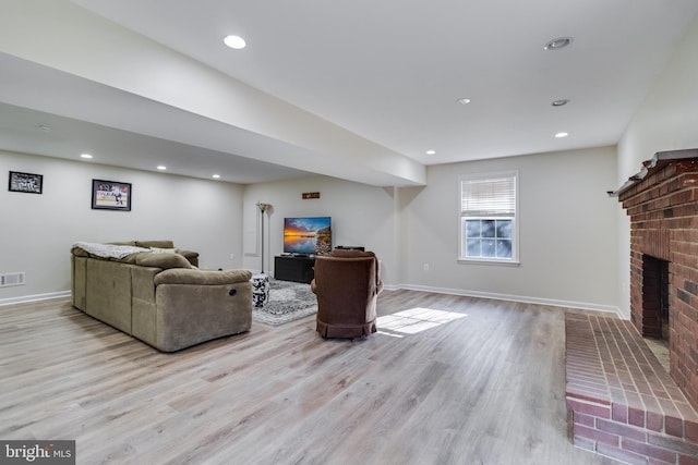 living room featuring a brick fireplace and light hardwood / wood-style flooring