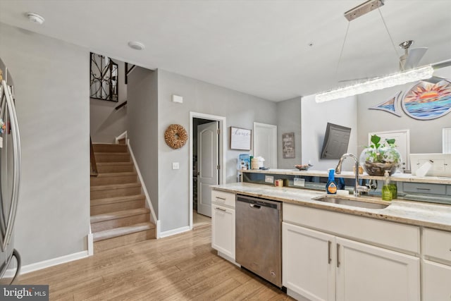 kitchen featuring light stone countertops, appliances with stainless steel finishes, sink, light hardwood / wood-style flooring, and white cabinets