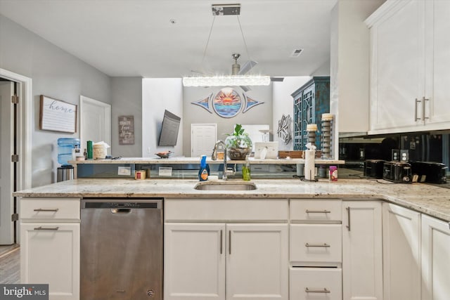 kitchen featuring light stone counters, white cabinetry, stainless steel dishwasher, and sink