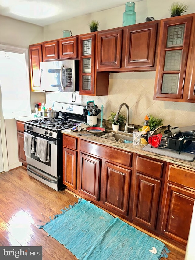 kitchen featuring light stone counters, sink, light wood-type flooring, and appliances with stainless steel finishes