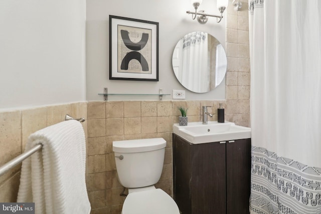 bathroom featuring vanity, tile walls, and toilet