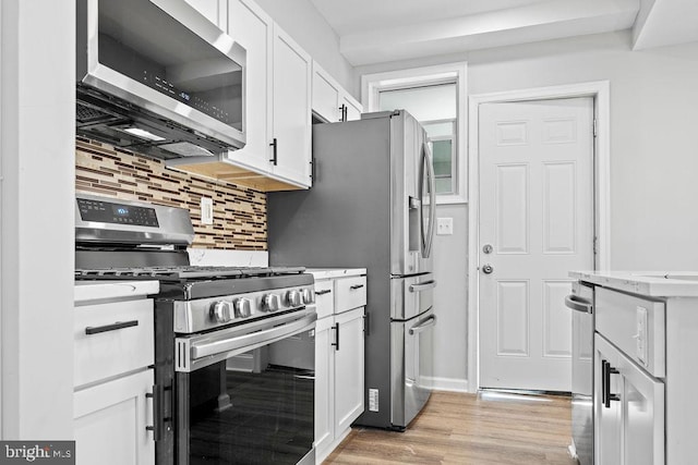 kitchen featuring stainless steel appliances, white cabinets, tasteful backsplash, and light hardwood / wood-style flooring