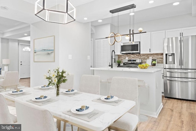 dining space with light hardwood / wood-style floors and crown molding