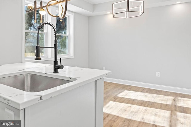 kitchen featuring sink, pendant lighting, light stone counters, and a chandelier