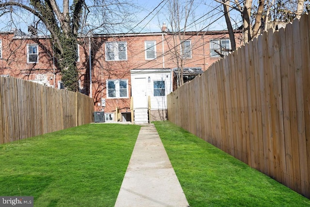 rear view of property with central AC and a lawn