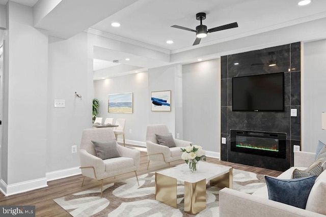 living room with a fireplace, ceiling fan, ornamental molding, and hardwood / wood-style floors