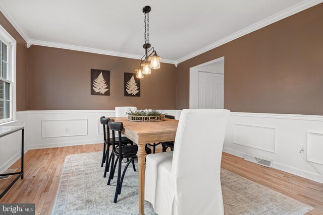 dining area featuring light wood-type flooring and ornamental molding