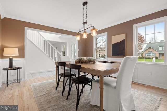 dining space with light hardwood / wood-style floors and crown molding