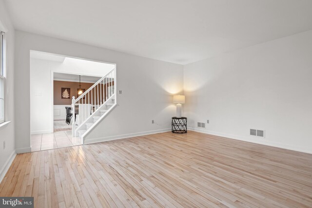 empty room with light hardwood / wood-style flooring and an inviting chandelier