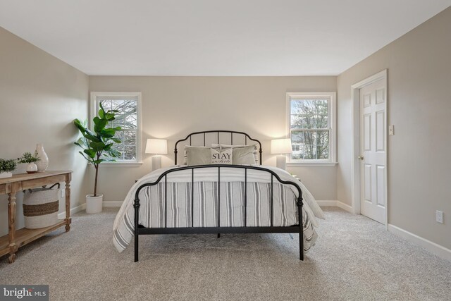 bedroom featuring light colored carpet and multiple windows