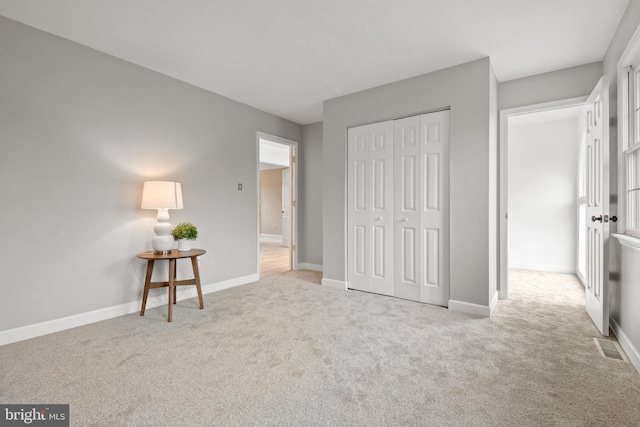 unfurnished bedroom featuring a closet and light colored carpet