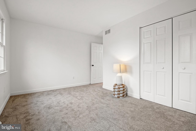 unfurnished bedroom featuring light colored carpet and a closet