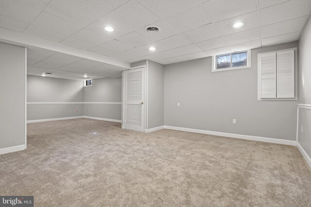 basement featuring a paneled ceiling and carpet floors