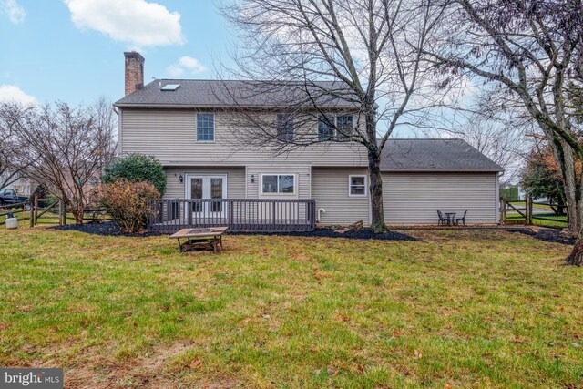 back of property with a yard and a wooden deck