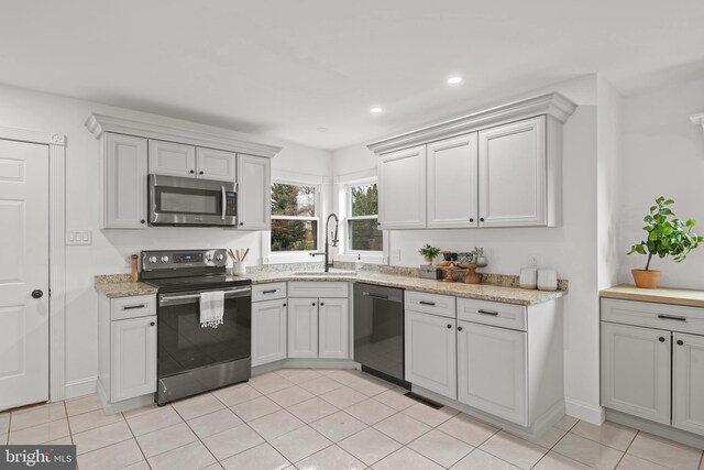 kitchen with sink, light tile patterned floors, light stone counters, white cabinets, and appliances with stainless steel finishes