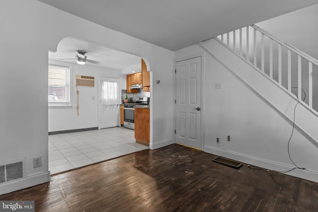 unfurnished living room featuring a wall mounted air conditioner, ceiling fan, and light hardwood / wood-style flooring