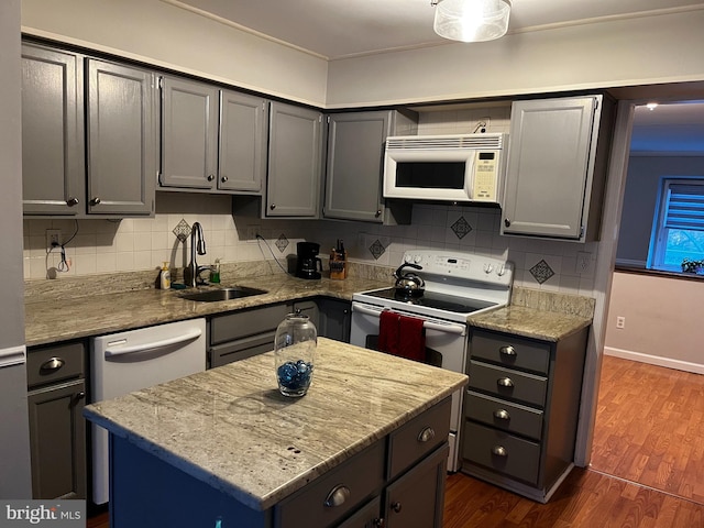 kitchen with sink, dark wood-type flooring, electric range oven, light stone counters, and a kitchen island