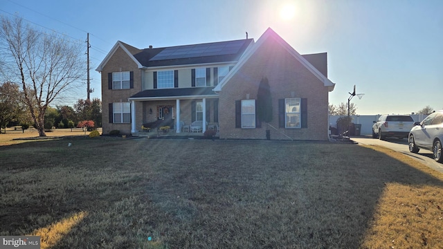 view of front facade featuring a front lawn, covered porch, and solar panels