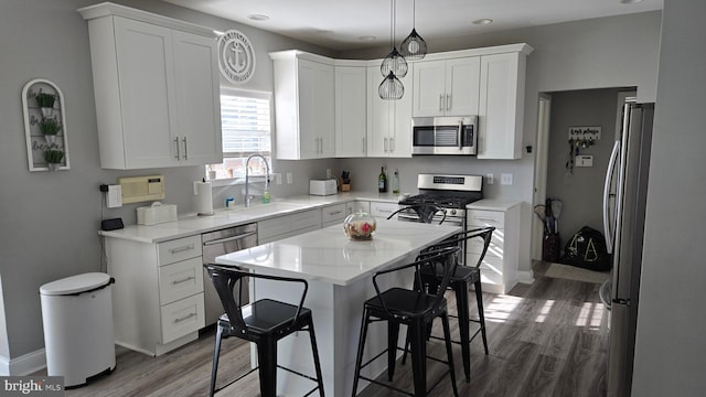 kitchen with white cabinets, appliances with stainless steel finishes, hanging light fixtures, and sink