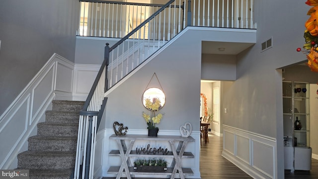 staircase featuring hardwood / wood-style flooring and a towering ceiling