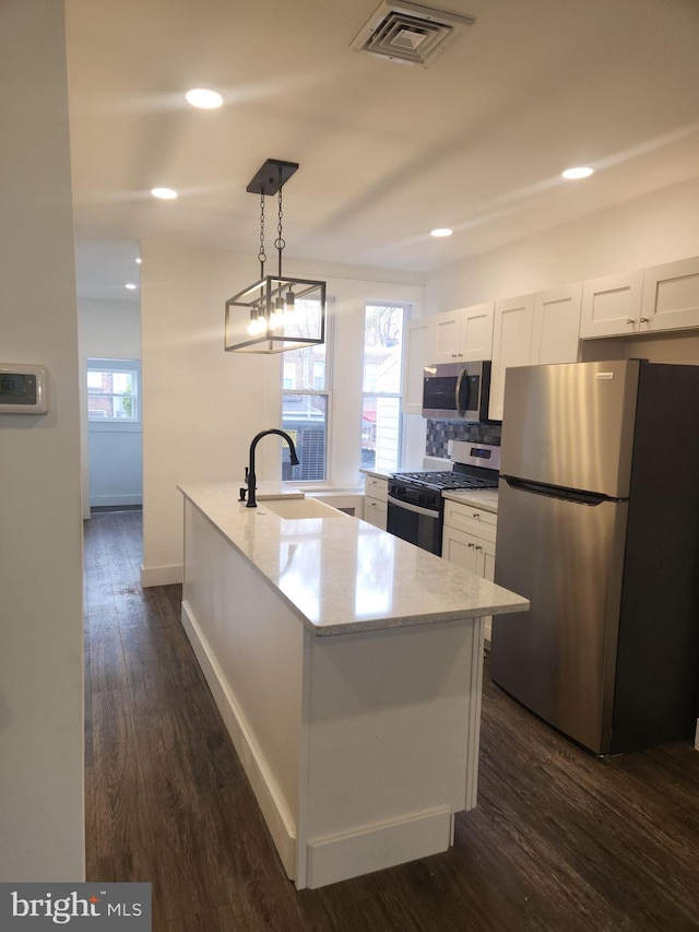 kitchen with pendant lighting, a center island with sink, dark hardwood / wood-style floors, white cabinetry, and stainless steel appliances