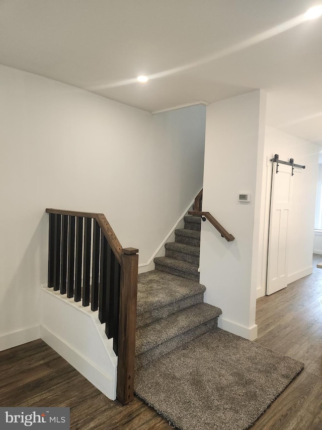 stairway with a barn door and wood-type flooring