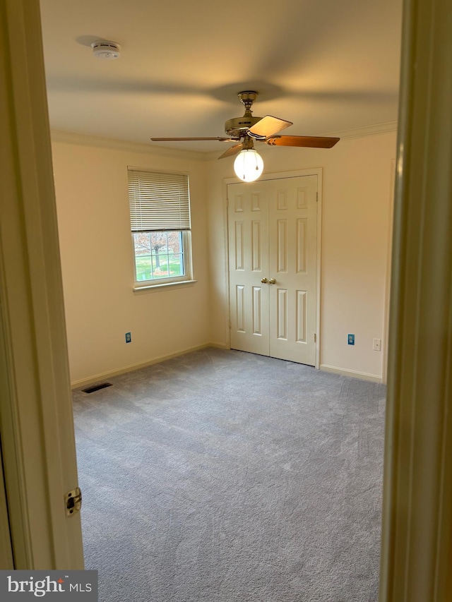 unfurnished bedroom with ceiling fan, carpet floors, and crown molding