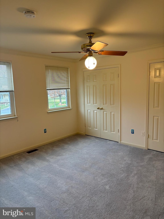 unfurnished bedroom featuring carpet flooring, ceiling fan, and ornamental molding