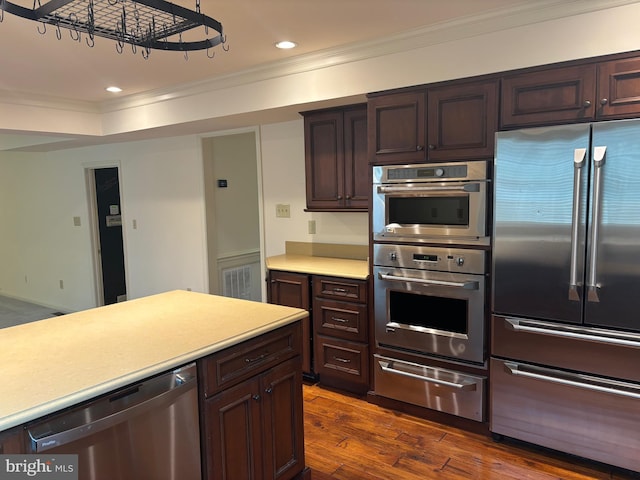 kitchen featuring crown molding, dark brown cabinets, dark wood-type flooring, and appliances with stainless steel finishes