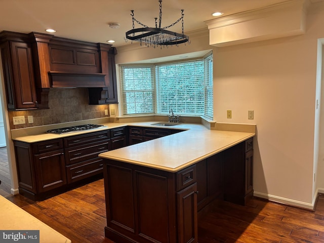 kitchen featuring dark wood-type flooring, crown molding, sink, tasteful backsplash, and kitchen peninsula