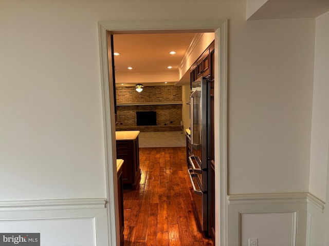 corridor with dark wood-type flooring and brick wall