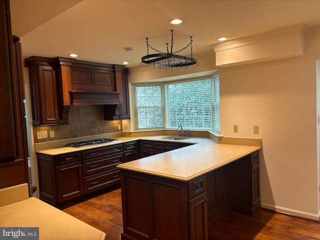 kitchen with sink, tasteful backsplash, dark hardwood / wood-style flooring, kitchen peninsula, and stainless steel gas stovetop