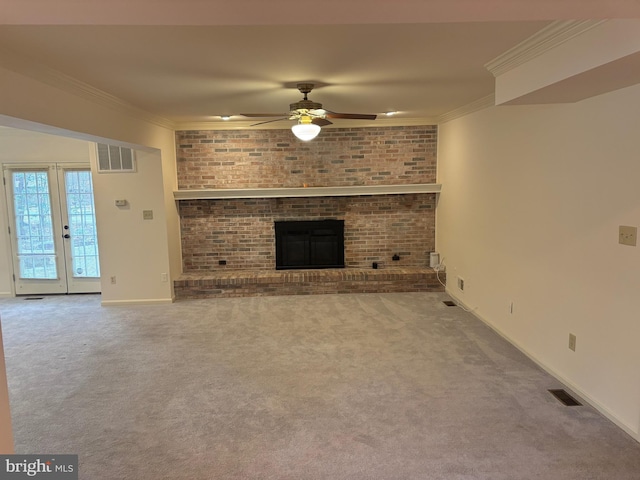 unfurnished living room with a brick fireplace, brick wall, ceiling fan, crown molding, and carpet floors