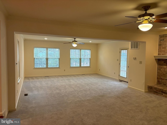 unfurnished living room with light carpet, a fireplace, ceiling fan, and ornamental molding