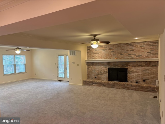 unfurnished living room featuring carpet flooring, brick wall, ceiling fan, crown molding, and a fireplace