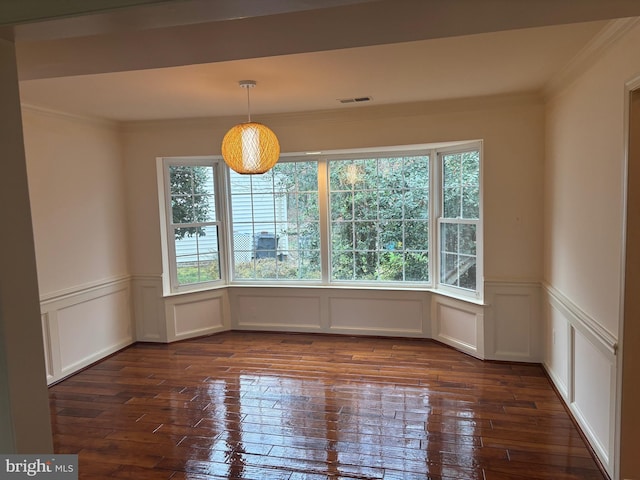 unfurnished dining area with a healthy amount of sunlight, ornamental molding, and dark wood-type flooring