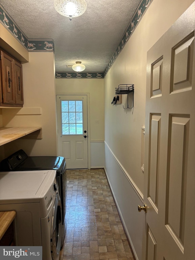 laundry room featuring cabinets, a textured ceiling, and separate washer and dryer